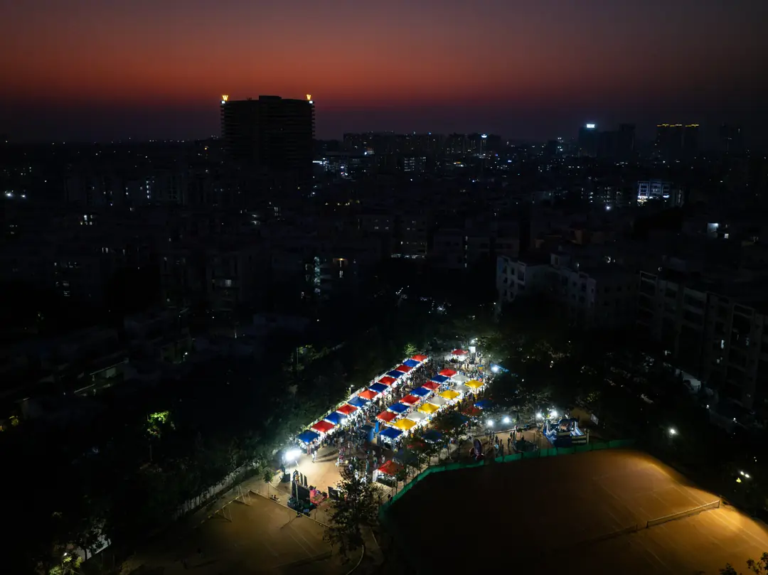 Aerial view at sunset of a lit community carnival between residential towers